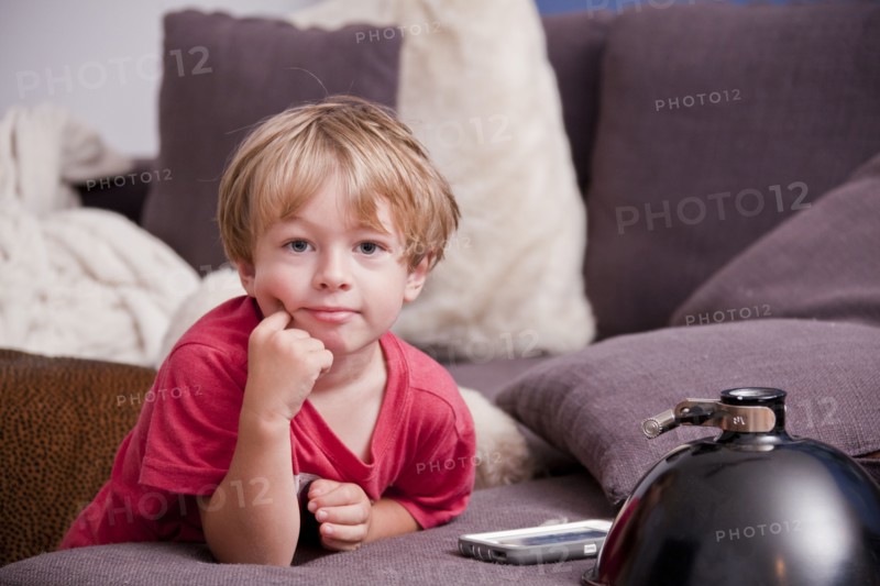 Caucasian boy leaning on sofa near cell phone
