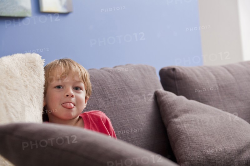 Caucasian boy with tongue out on sofa