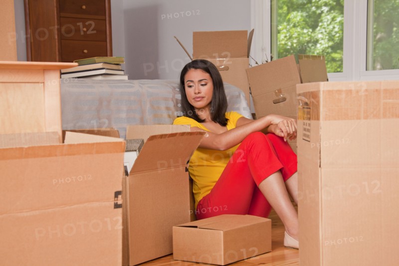 Hispanic woman sitting on floor with moving boxes