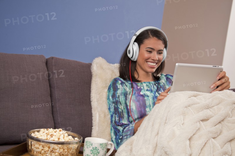 Smiling Hispanic woman sitting on sofa with digital tablet