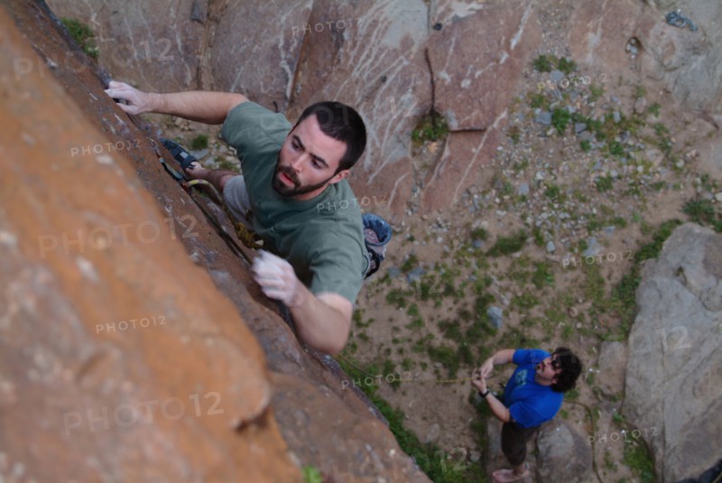 Spotter watching friend climbing urban brick wall