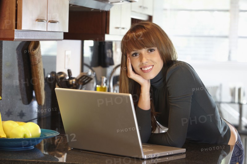 Mixed race woman with laptop in kitchen