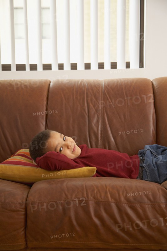 Mixed race boy laying on couch