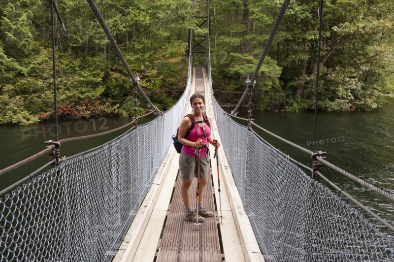 Hispanic woman hiking over bridge in woods