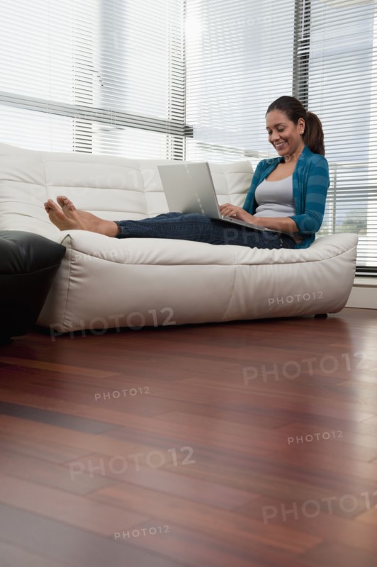 Hispanic woman on sofa using laptop