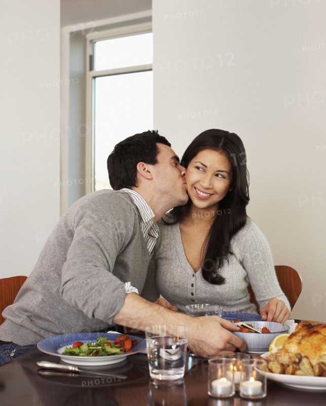 Husband kissing wife at dinner table