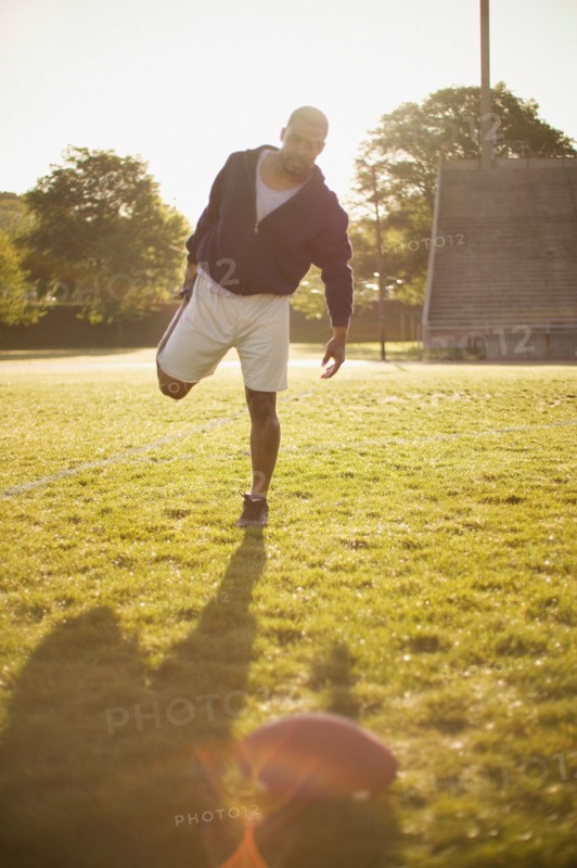 Man stretching on football field