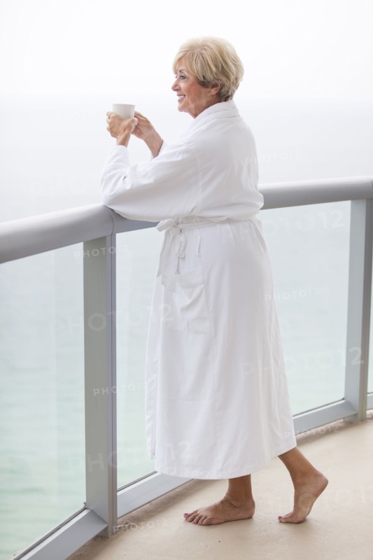 Older Caucasian woman drinking coffee on balcony