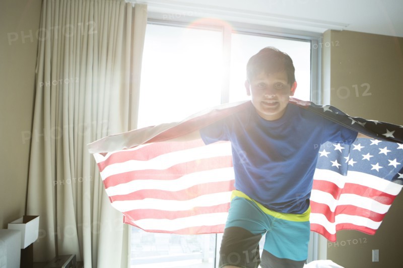 Hispanic boy using American flag as cape