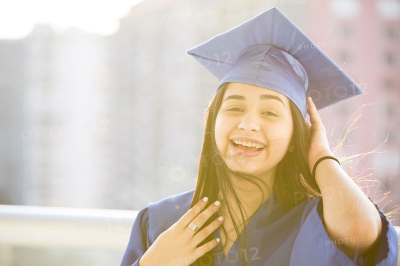 Smiling Hispanic girl wearing graduation robe and mortarboard