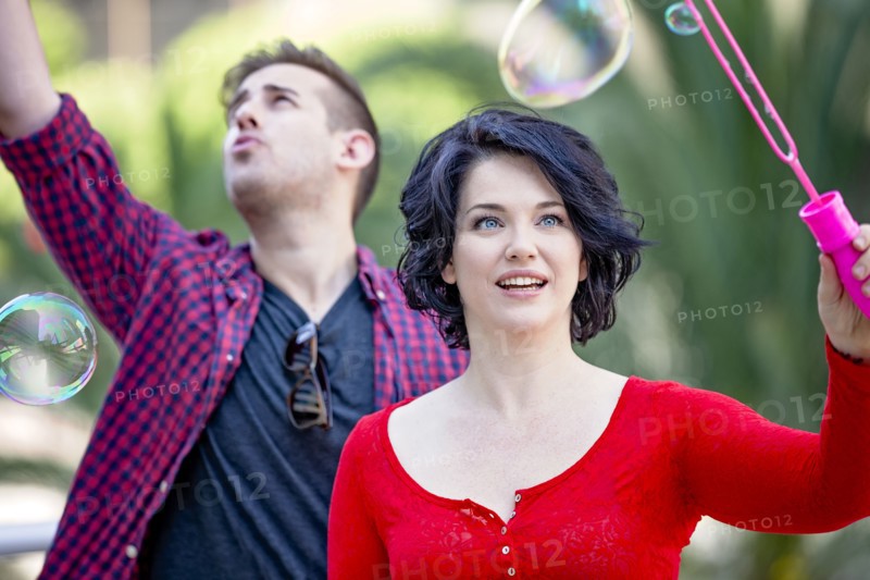 Caucasian couple blowing bubbles outdoors