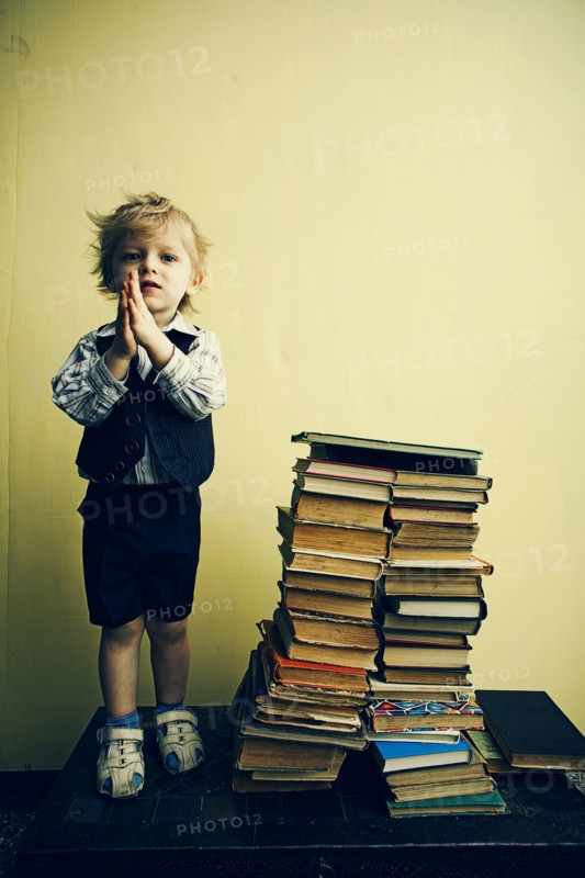 Boy standing near stacks of books