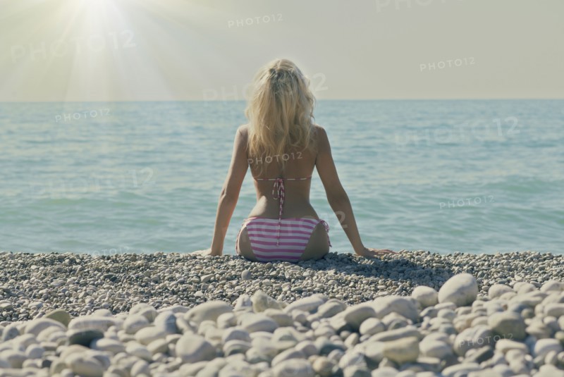 Caucasian woman sitting on rocky beach