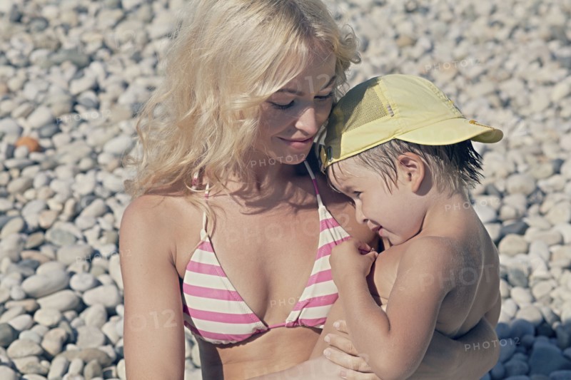Mother holding son on rocky beach