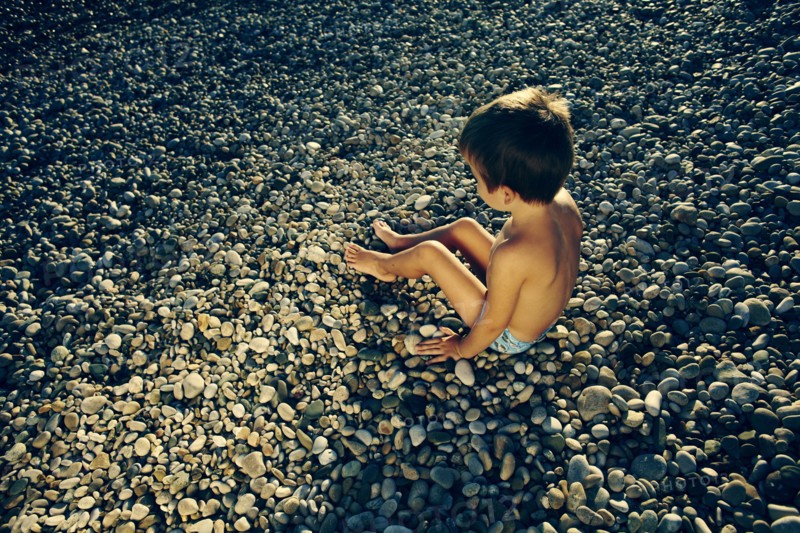 High angle view of boy sitting on rocky beach
