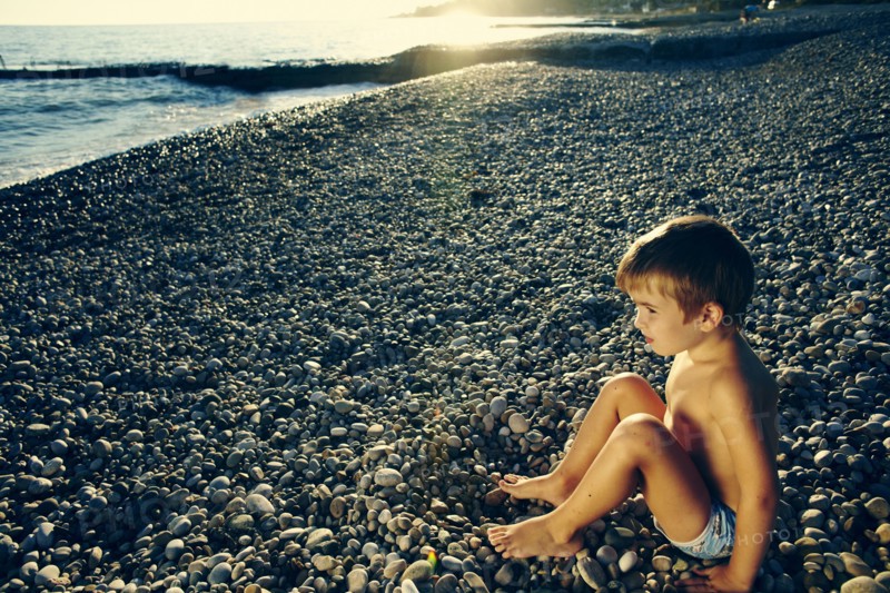 High angle view of boy sitting on rocky beach
