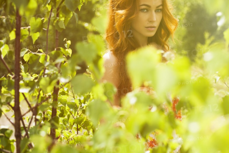 Caucasian woman posing behind foliage