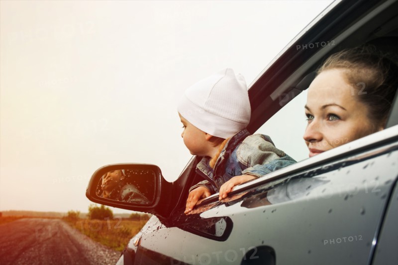 Caucasian mother and son looking out car window