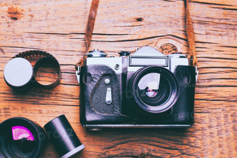 Camera with lens and film on wooden table