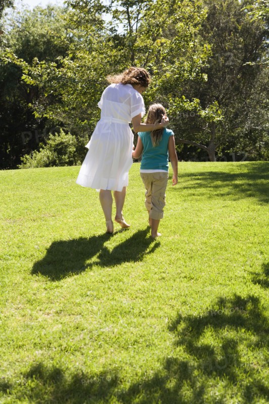 Mother and daughter walking together in grass