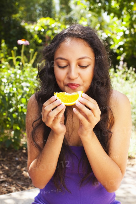 Mixed race teenager eating orange