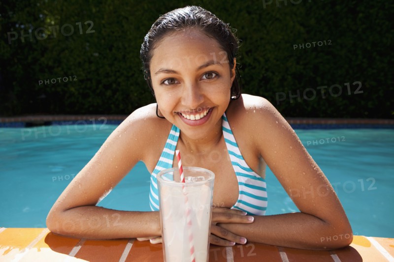 Mixed race girl drinking lemonade near swimming pool