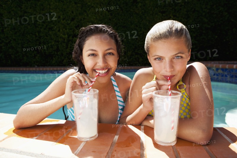 Girls drinking lemonade near swimming pool