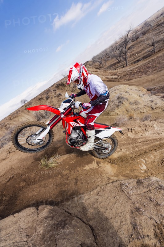 Motorcyclist riding dirt bike on hillside