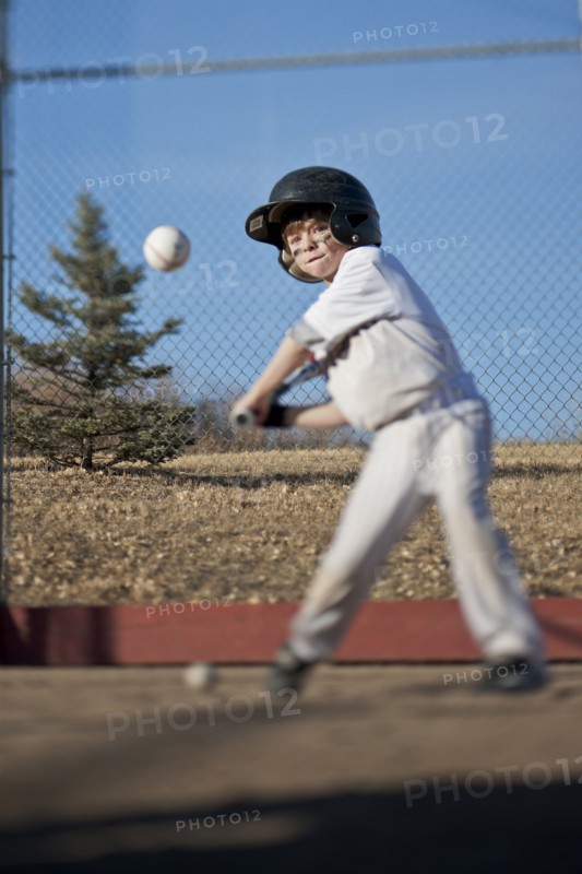 Caucasian boy hitting baseball on field