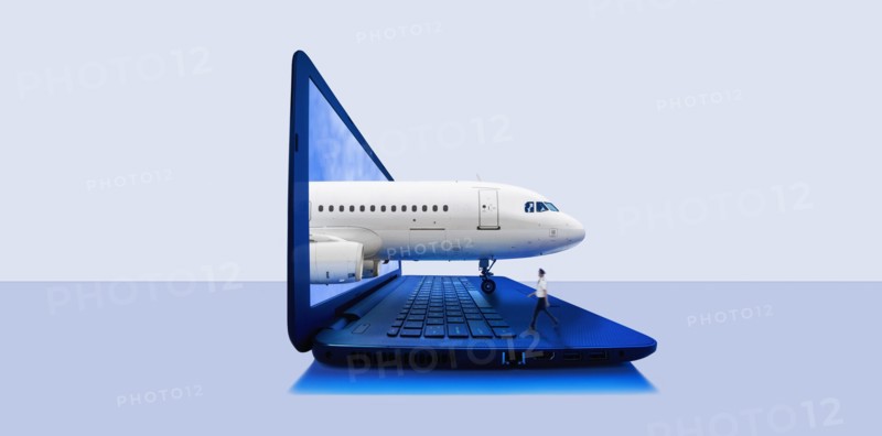 Airplane emerging from laptop screen with pilot walking on keyboard