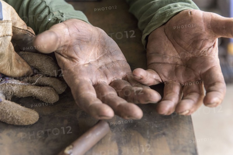 Artist leaning on table in workshop showing rugged hands