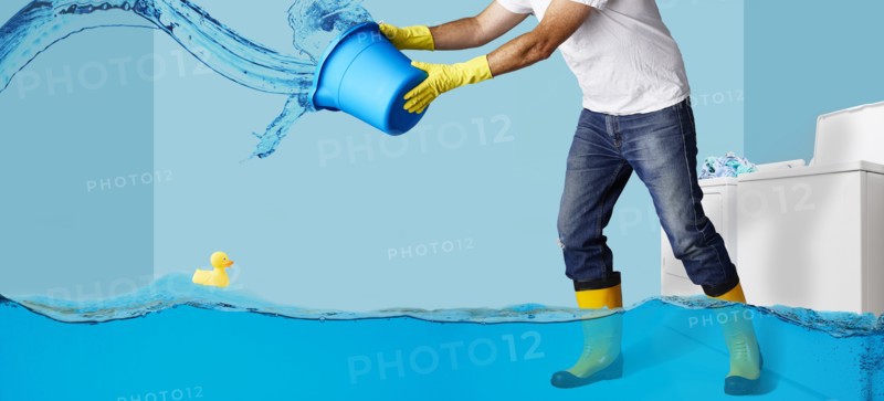 Man throwing water from bucket in flooding laundry room