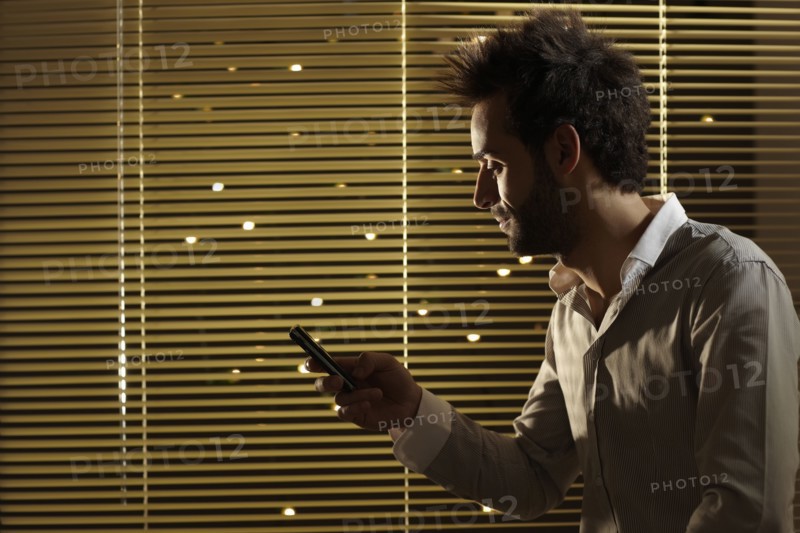 Caucasian man text messaging on cell phone at night