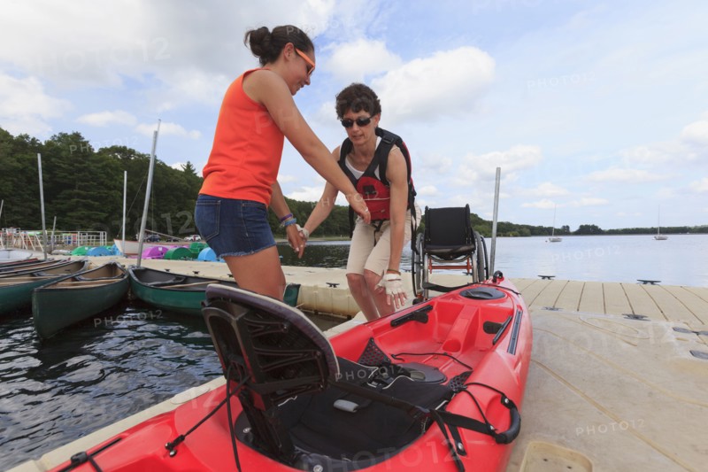 Caucasian instructor helping paraplegic woman with kayak