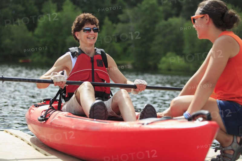 Caucasian instructor helping paraplegic woman with kayak