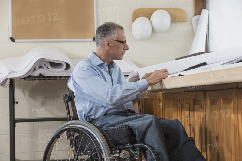 Caucasian architect in wheelchair working in office