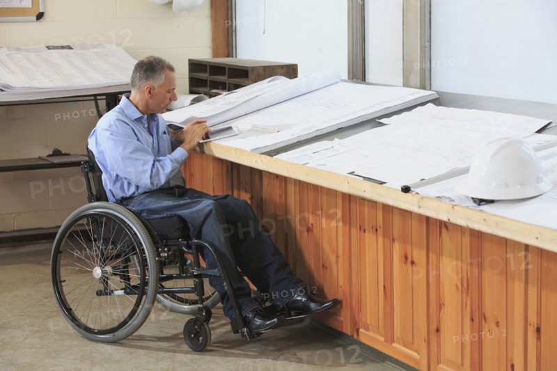 Caucasian architect in wheelchair working in office