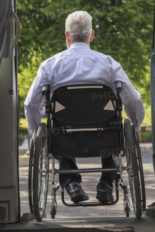 Caucasian businessman in wheelchair exiting van