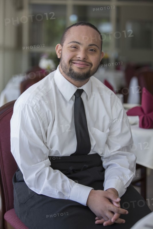 Mixed race server with down syndrome smiling in restaurant