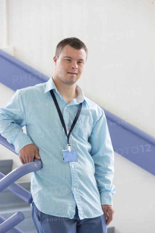 Caucasian man with Down Syndrome wearing badge on stairs
