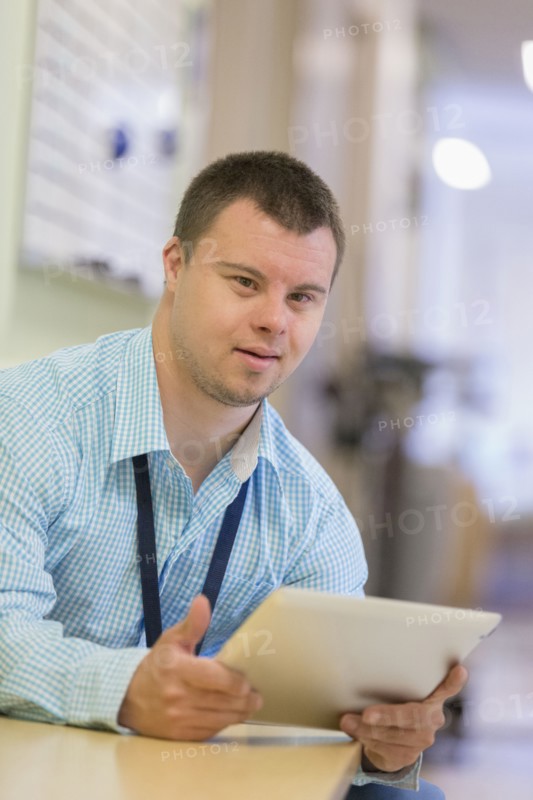 Caucasian man with Down Syndrome using digital tablet in hospital