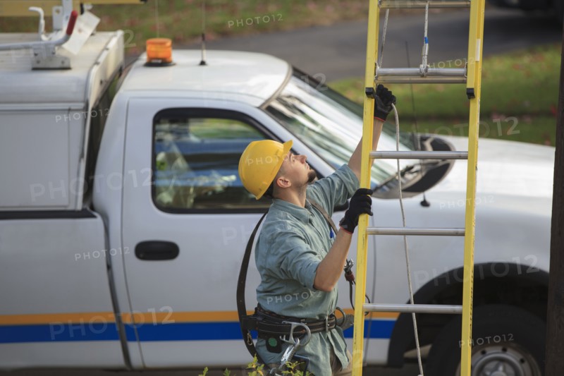 Caucasian worker raising ladder outdoors