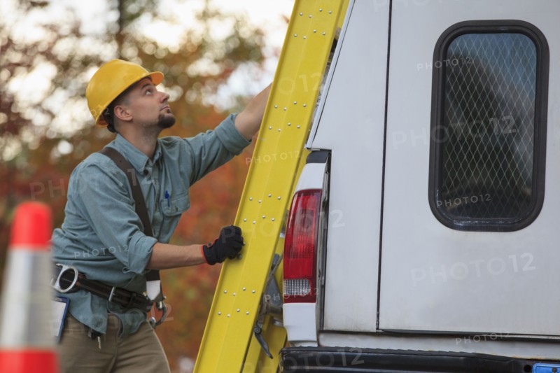 Caucasian worker loading ladder on truck