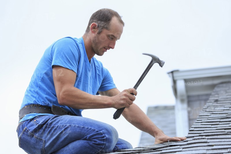 Deaf Caucasian roofer hammering on roof