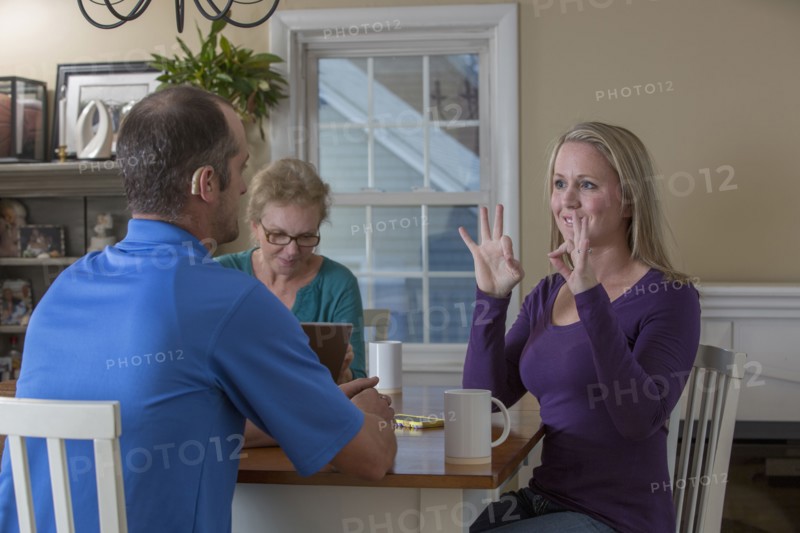 Deaf Caucasian friends signing at dinner table