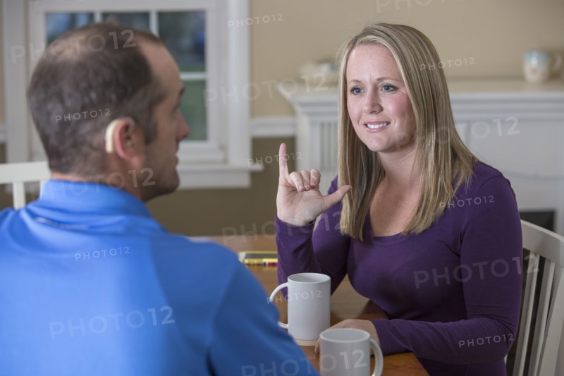 Deaf Caucasian couple signing at dinner table