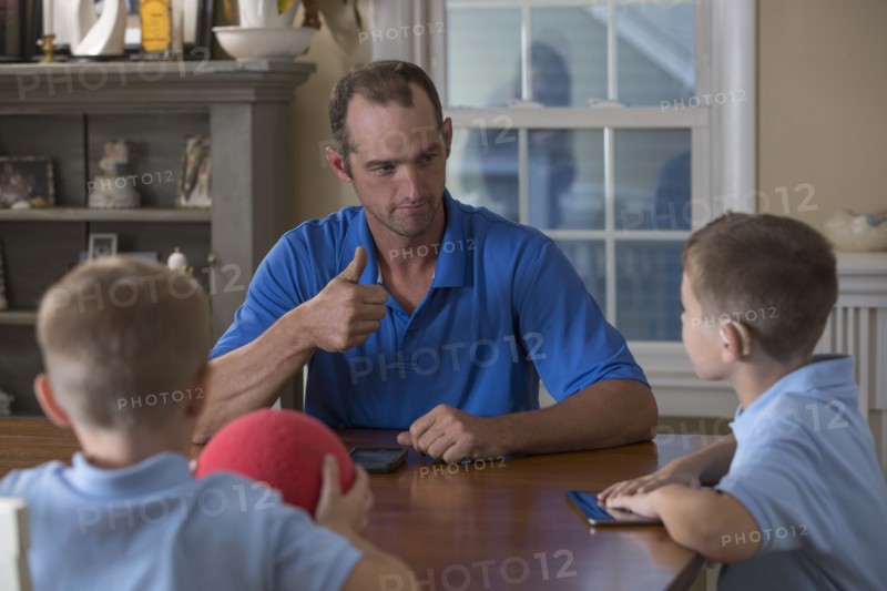 Caucasian father and sons signing at dinner table