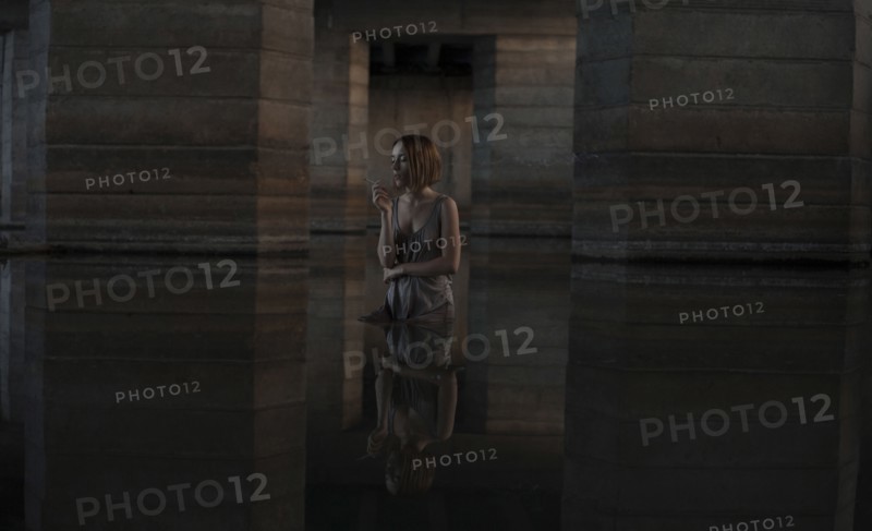Caucasian woman standing in water smoking cigarette