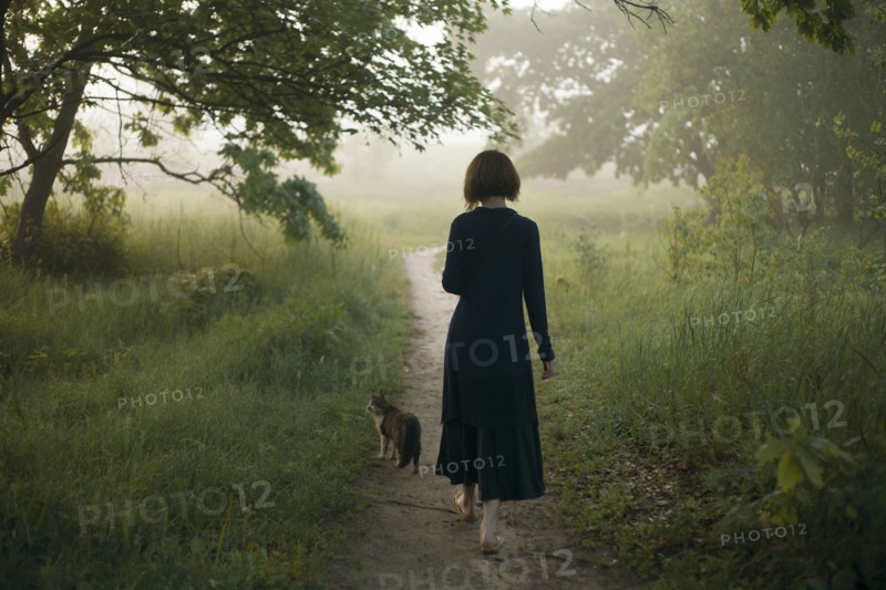 Woman and cat walking on path in fog