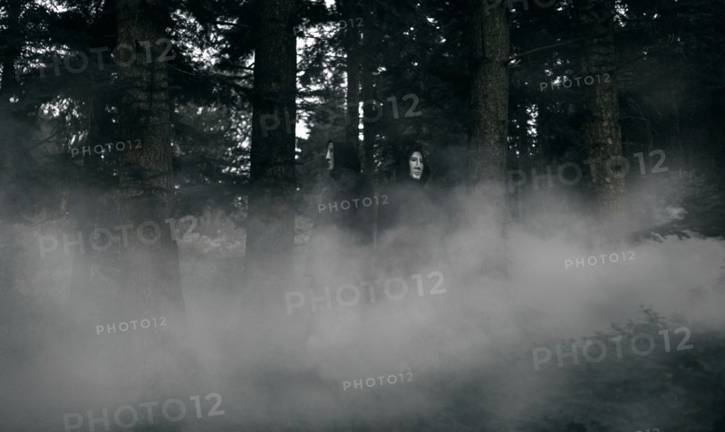 People wearing black robes and white masks in foggy forest